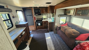 Un intérieur de camping-car compact comprenant un coin cuisine, un espace repas et un coin nuit.