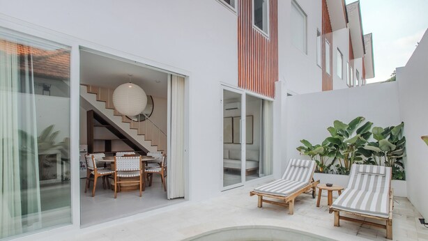 A modern house with a pool, two lounge chairs, and a dining area with chairs and a table. - A.K.A Cemagi Townhouse (Cemagi)