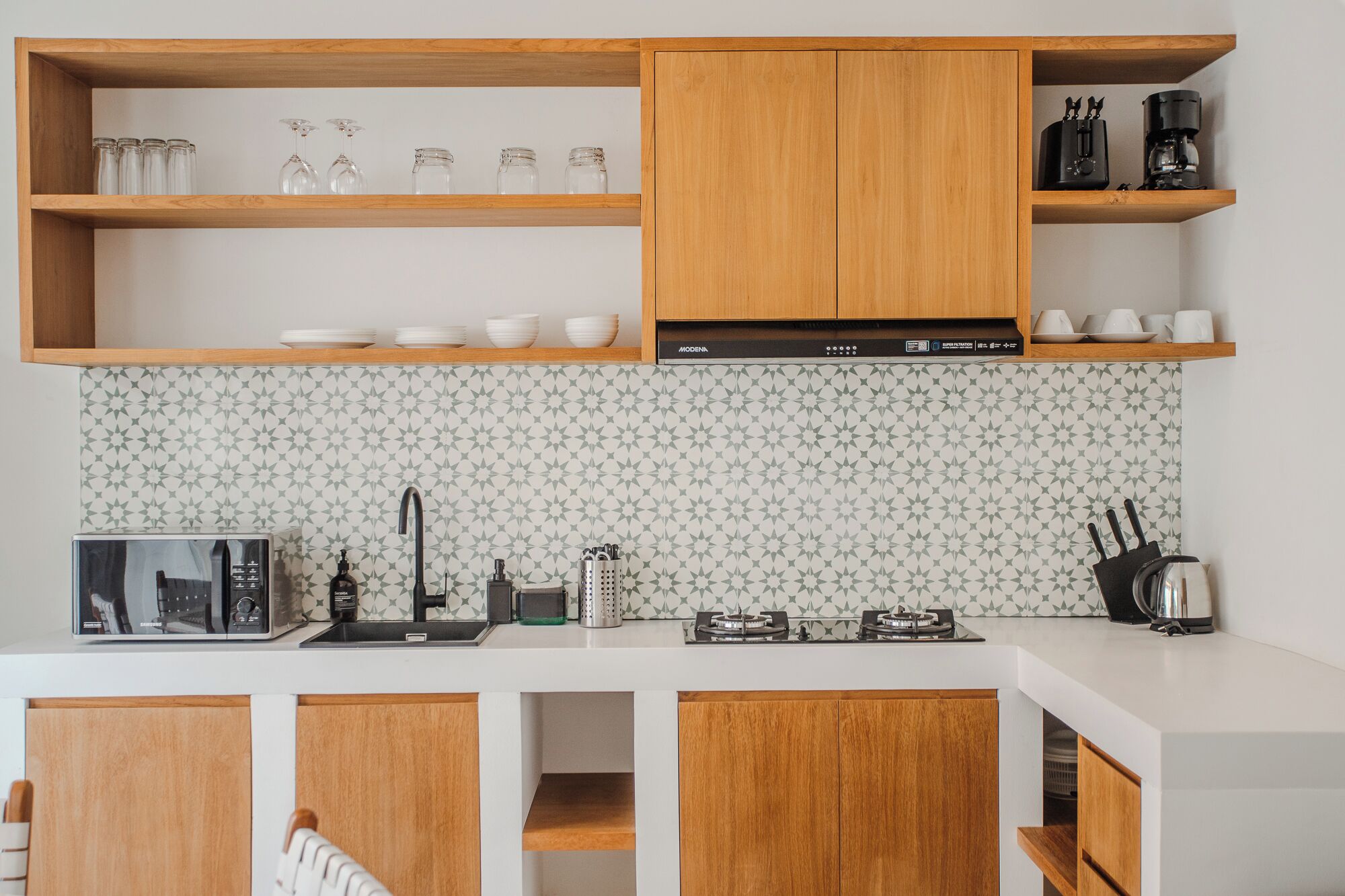 Una cocina moderna con armarios de madera, microondas, estufa a gas y cafetera.
