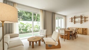A modern living room with a sofa, armchairs, a coffee table, and a dining area with a wooden table and chairs. - A.K.A Cemagi Townhouse (Cemagi)