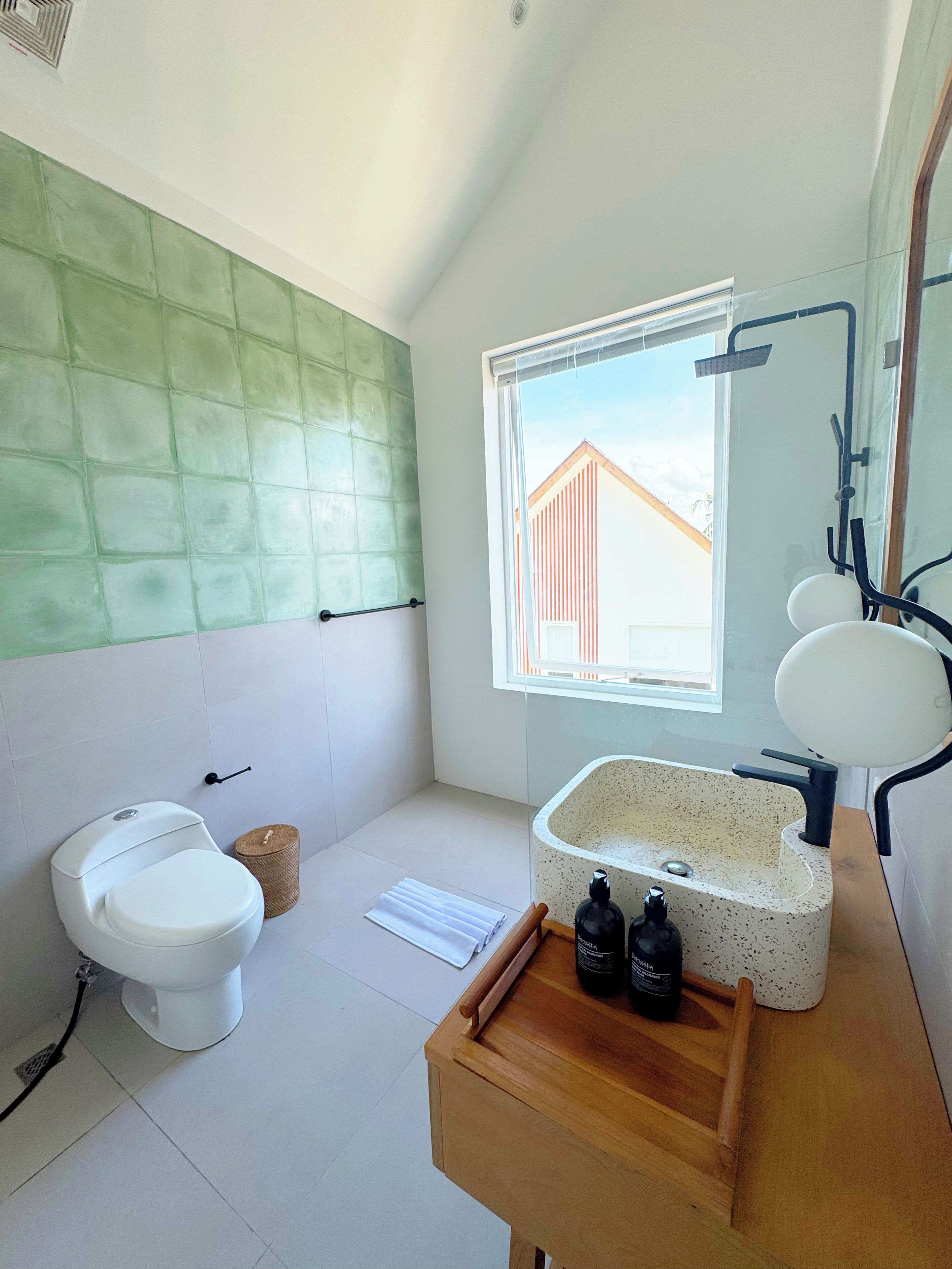 A modern bathroom with a toilet, sink, and window.