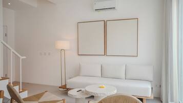 Una sala de estar moderna con un sofá blanco, dos cuadros enmarcados, una lámpara de pie y una mesa de centro redonda.