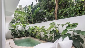 A small outdoor pool area with a white wall and lush greenery. - A.K.A Cemagi Townhouse (Cemagi)