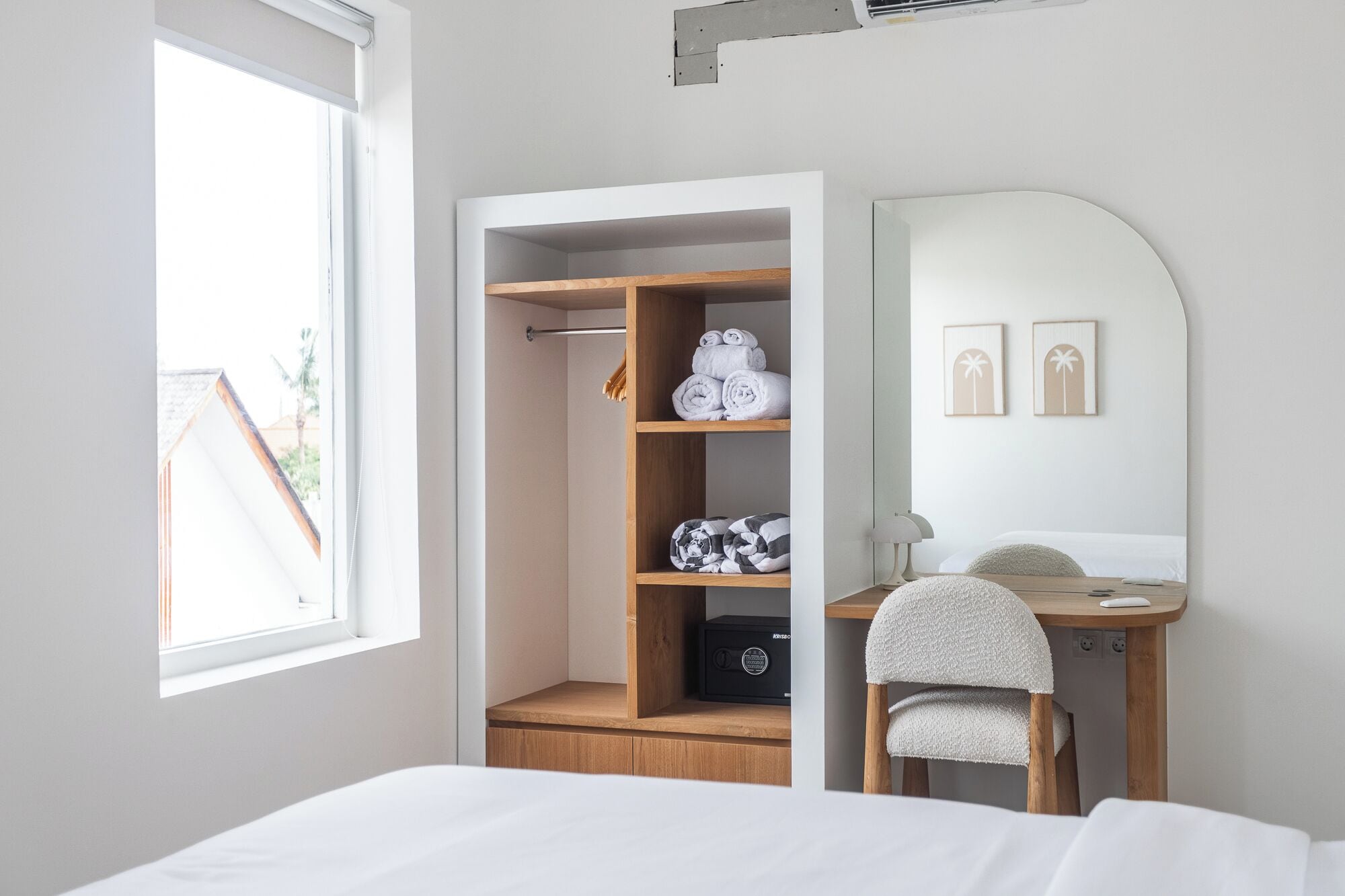 A bedroom with a bed, a desk with a chair, a wardrobe, and a mirror.