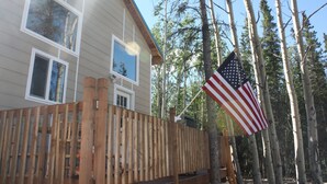 Una casa de dos pisos con un balcón de madera y un asta con la bandera estadounidense.