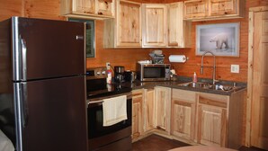 Una cocina compacta con armarios de madera, un refrigerador de acero inoxidable, un microondas y un lavamanos.