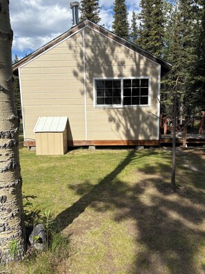 A small, single-story wooden cabin with a gabled roof, a front window, and a small porch area. - Denali Gnome Home (Healy)