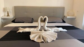 Ein Bett mit grauer Kopfteil, zwei Kissen und ein Handtuch, das zu einem Herzen geformt ist.