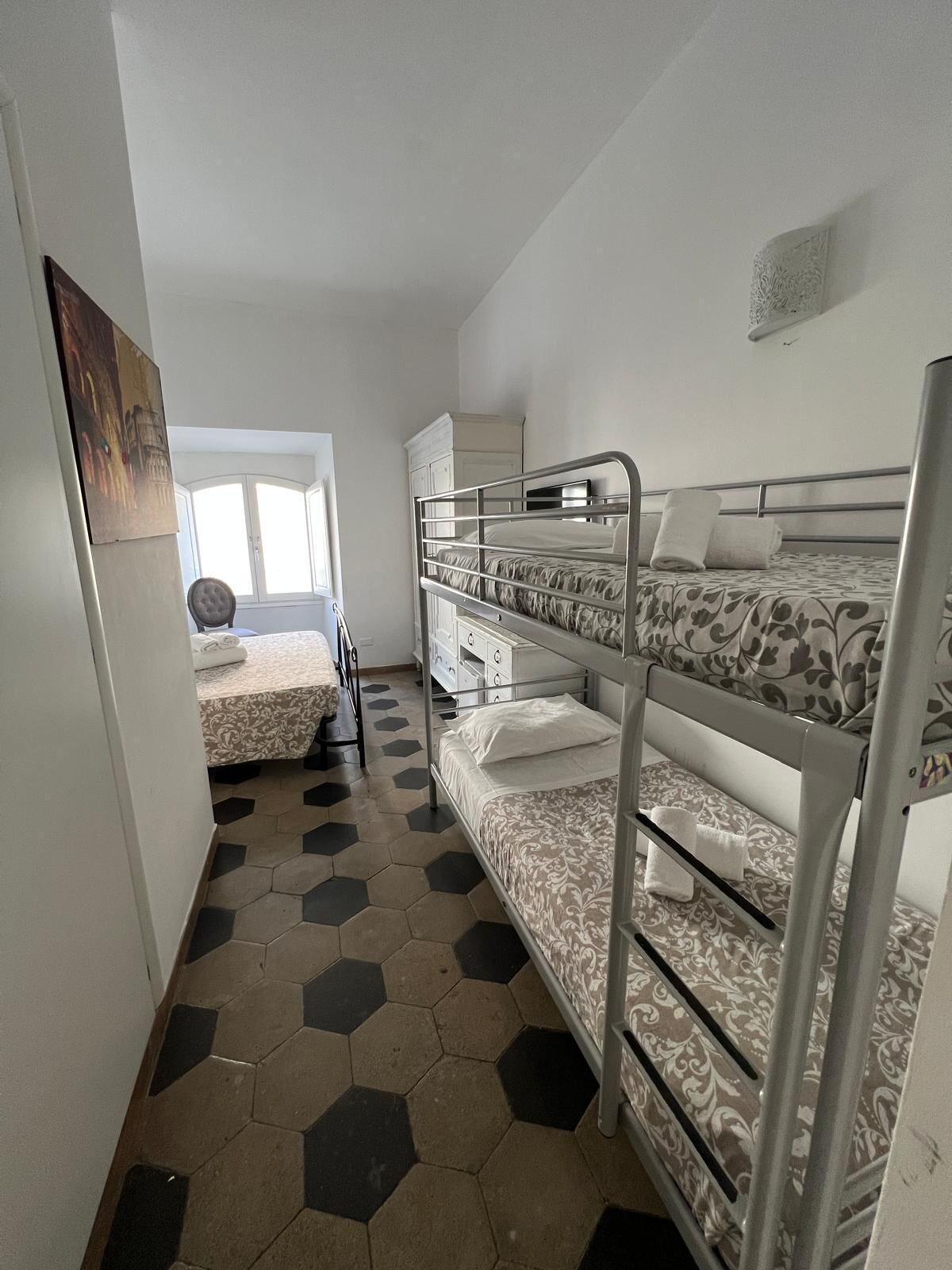 A room with bunk beds, a small desk, and a window.