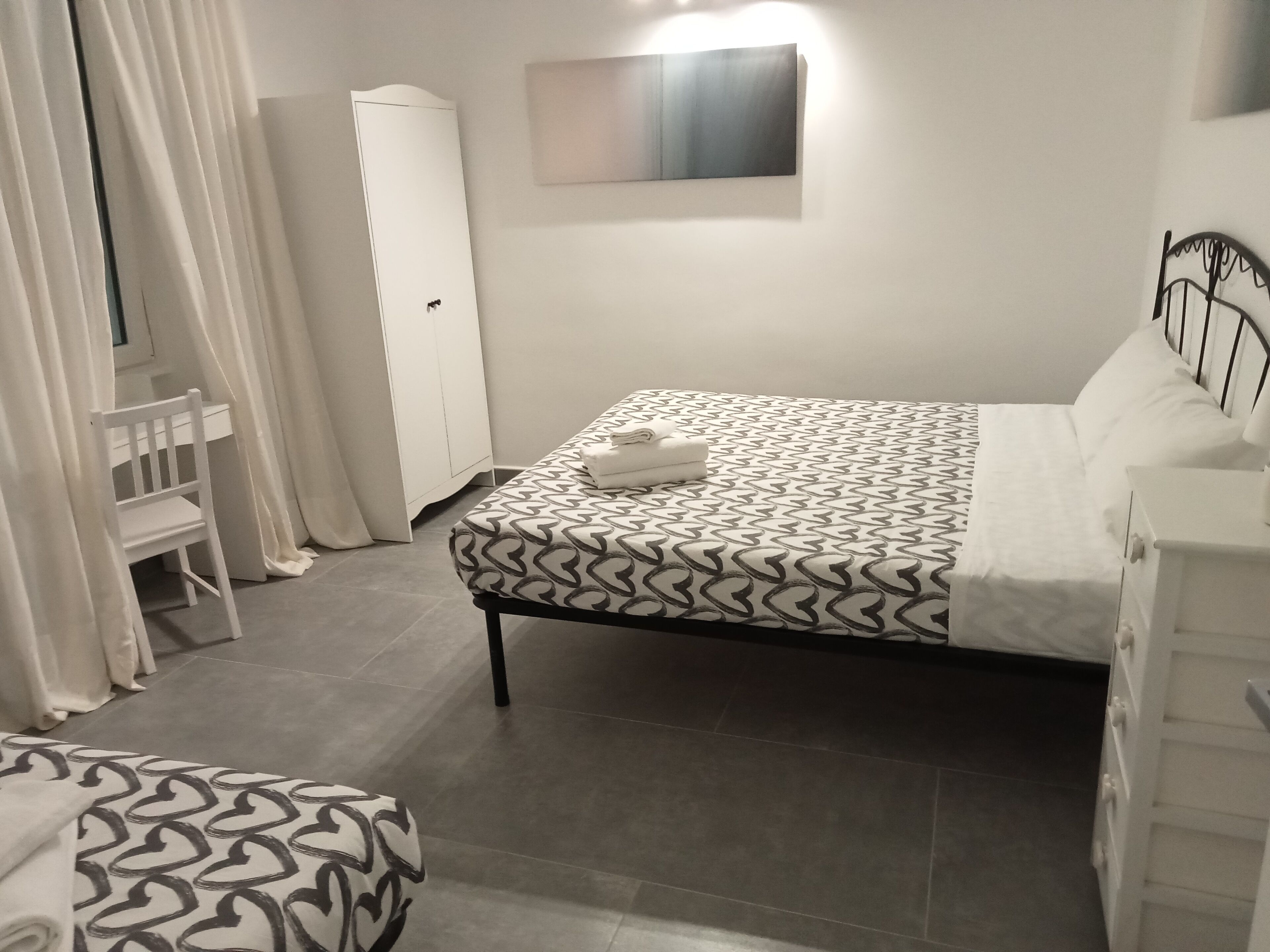 A bedroom with a bed, a chair, a wardrobe, and a bedside table.