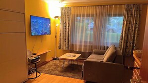 Ein Wohnzimmer mit einer Couch, einem Couchtisch, einem Fernseher und einer Lampe.