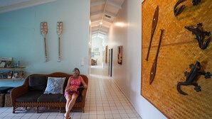 A spacious lobby with a central seating area, a long corridor, and a wall adorned with decorative items. - Muri Lagoon Lodge (Rarotonga)