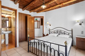 A bedroom with a metal bed frame, a wooden door, a white sink, and a mirror. - Countryside Apartment 1 With Shared Swimming Pool (Kissamos)