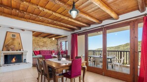 Uma sala de jantar com mesa e cadeiras de madeira, lareira e vista para o exterior.