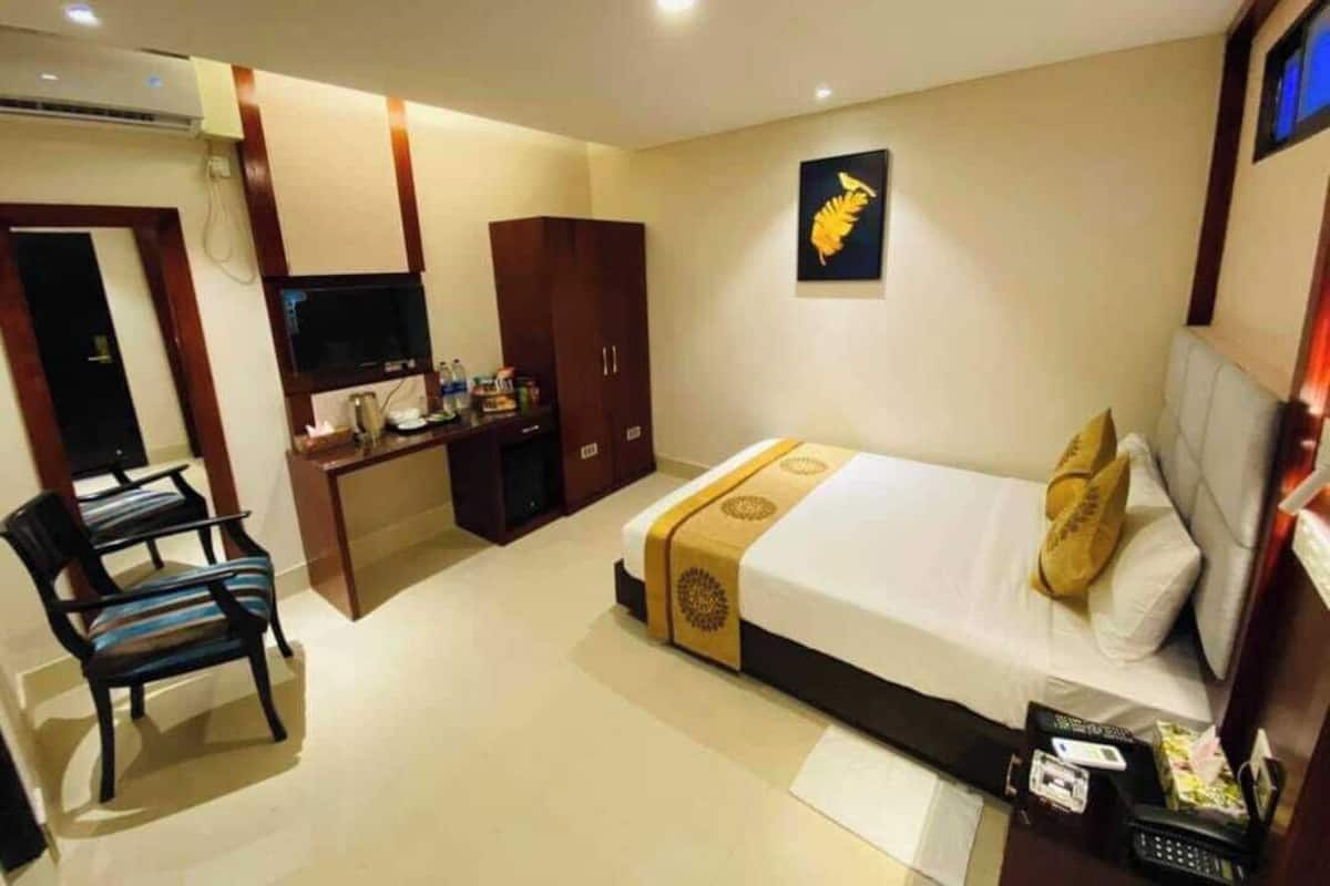 A hotel room with a bed, a desk, a TV, and a chair.