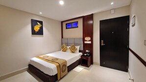 A hotel room with a bed, bedside table, nightstand, and a door. - Hotel Grand Royal Dhanmondi  (Dhaka)