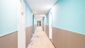 A long, narrow hallway with light blue walls and a beige carpet. - yimimopeichengdian (Guangzhou)