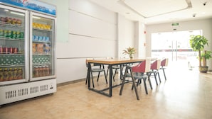 A clean, modern room with a table and chairs, a vending machine with beverages, and a potted plant. - yimimopeichengdian (Guangzhou)