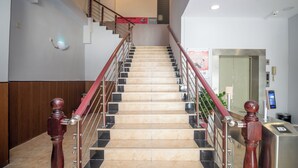 A staircase with marble steps, wooden balusters, and metal railings, leading to an elevator. - yimimopeichengdian (Guangzhou)