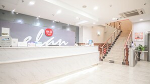 A hotel reception area with a marble counter, a staircase, and a wall with a logo. - yimimopeichengdian (Guangzhou)