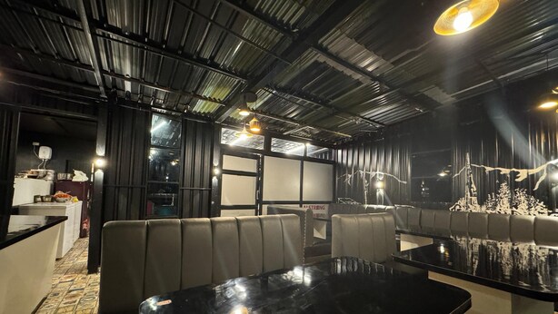 A restaurant interior with high ceilings, exposed beams, and modern lighting fixtures. - Hotel Jafson Accommodates (Srinagar)