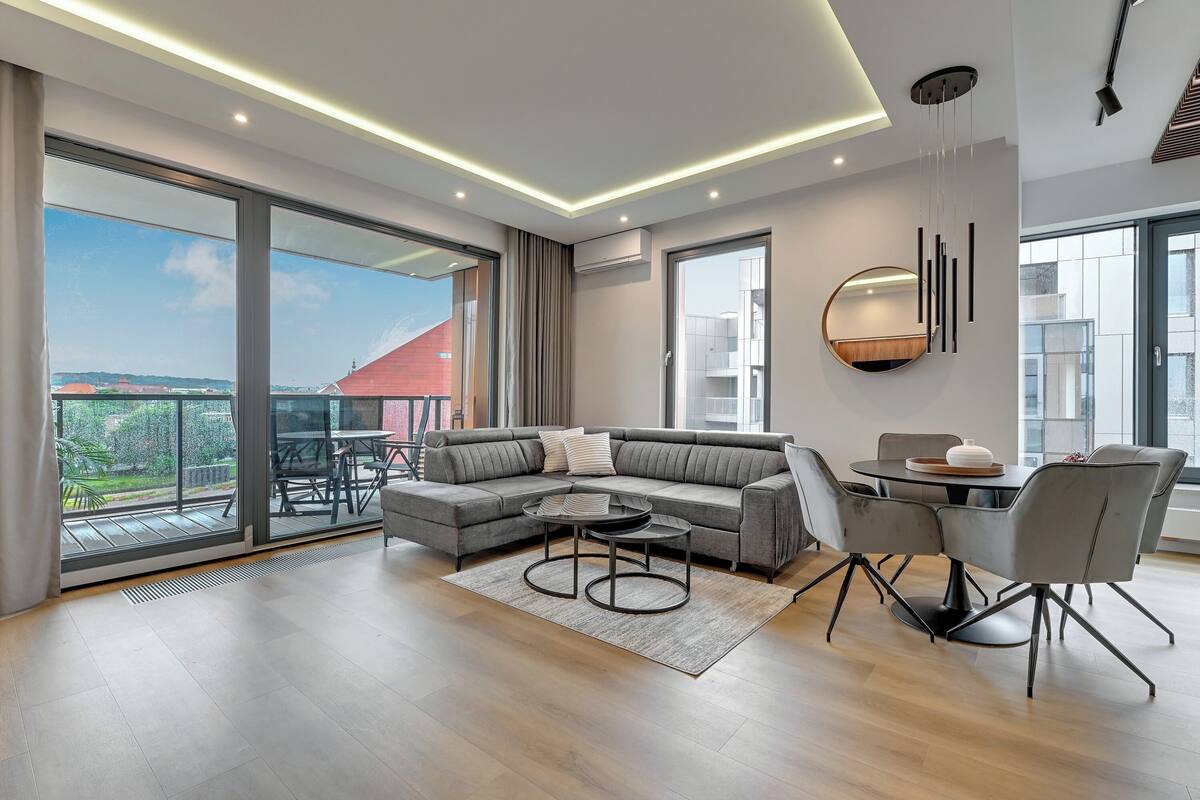 Una sala moderna con un sofá modular, una mesa de centro redonda y un comedor con sillas.