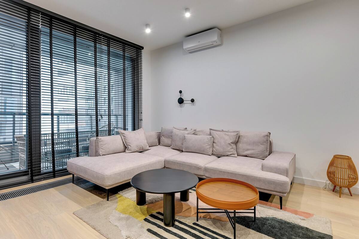 Una sala moderna con un sofá modular, una mesa de centro redonda y una mesita auxiliar.