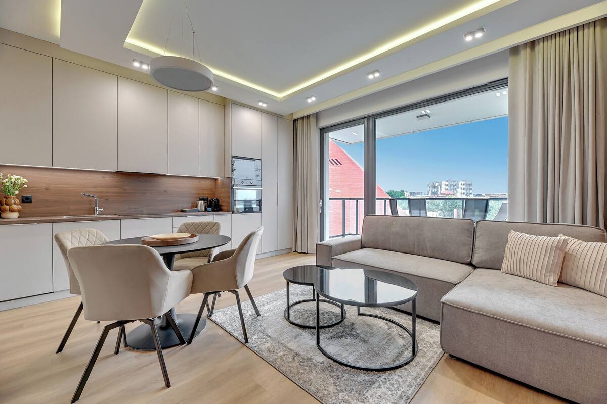 Una sala moderna con sofá, mesa de centro y comedor con sillas.