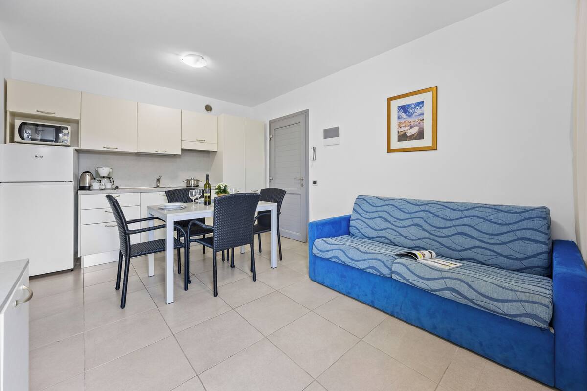 A compact living space with a kitchenette, dining area, and a sofa.