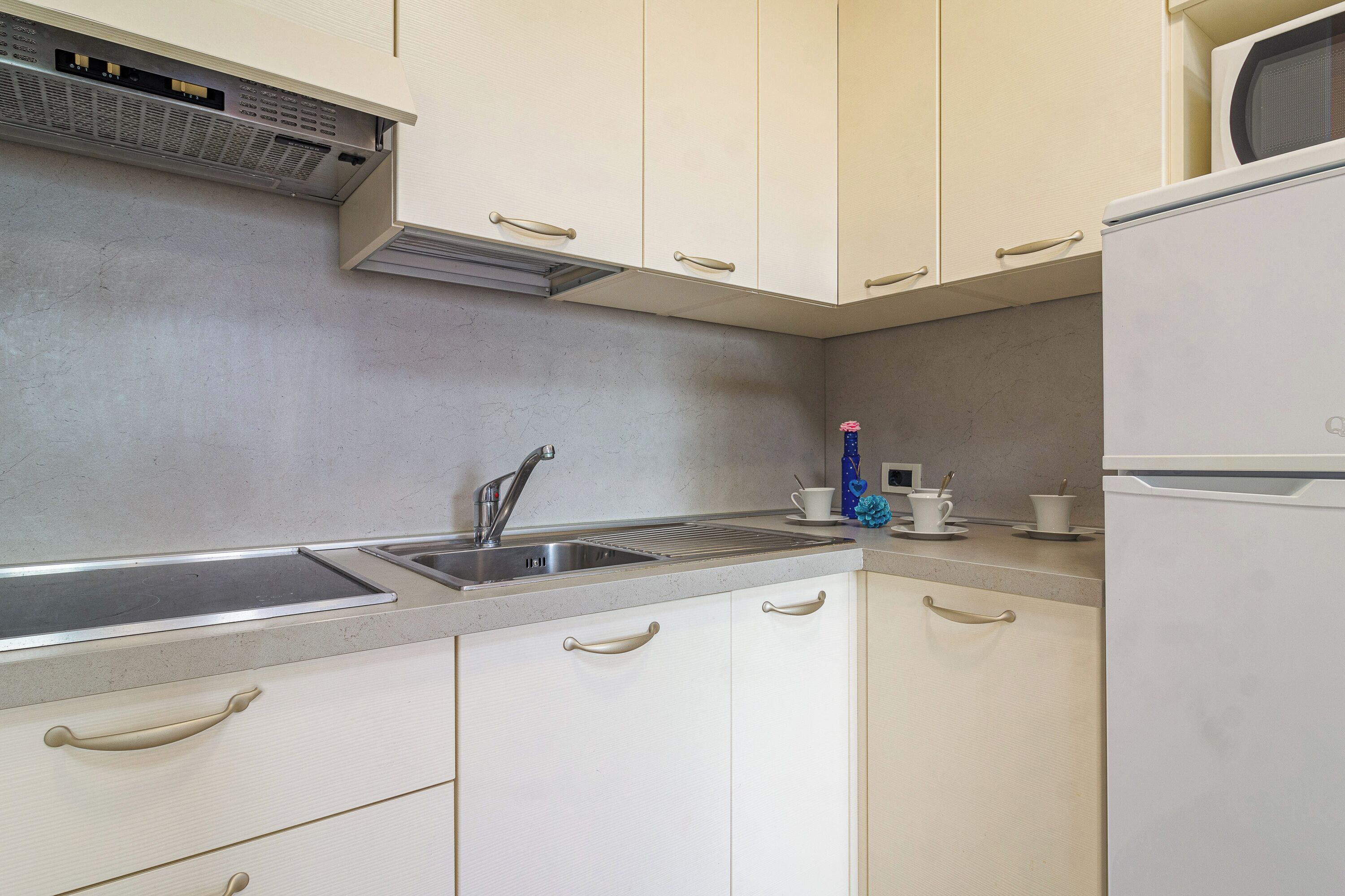 A kitchen with white cabinets, a stainless steel sink, and a microwave.