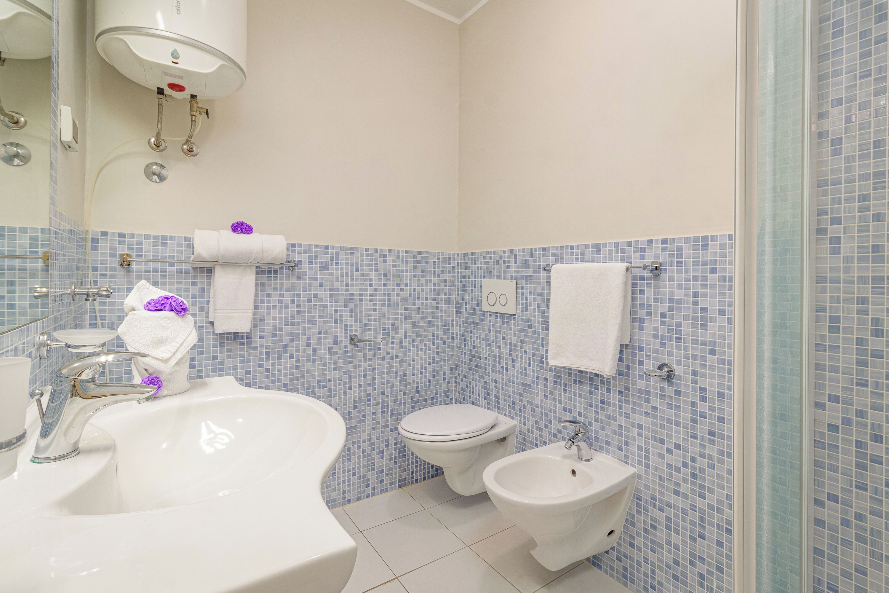 Een badkamer met een wastafel, toilet, bidet en een spiegel.