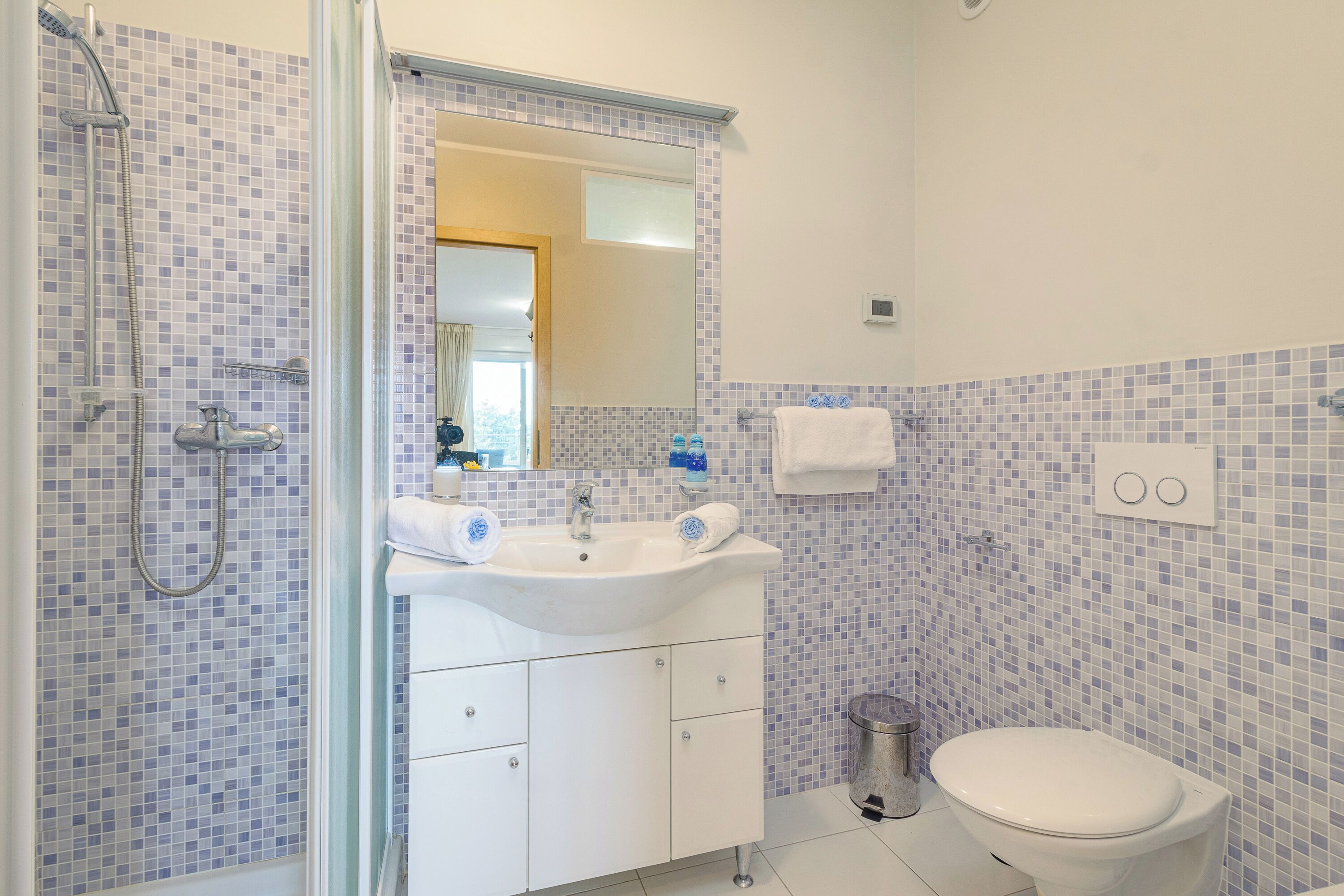 A bathroom with a shower, sink, and toilet.