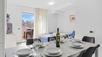 Comedor con una mesa lista para cuatro, una botella de vino y vistas al exterior.