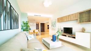 Uma sala de estar moderna com sofá, mesa de centro, TV e objetos decorativos.