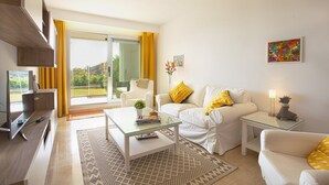 A modern living room with a glass coffee table, white sofas, and a television. - Ojén Apartment Near Golf (Ojen)