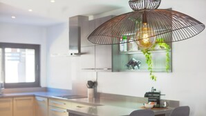 Een moderne keuken met een centraal eiland, hanglampen en uitzicht op de omgeving.