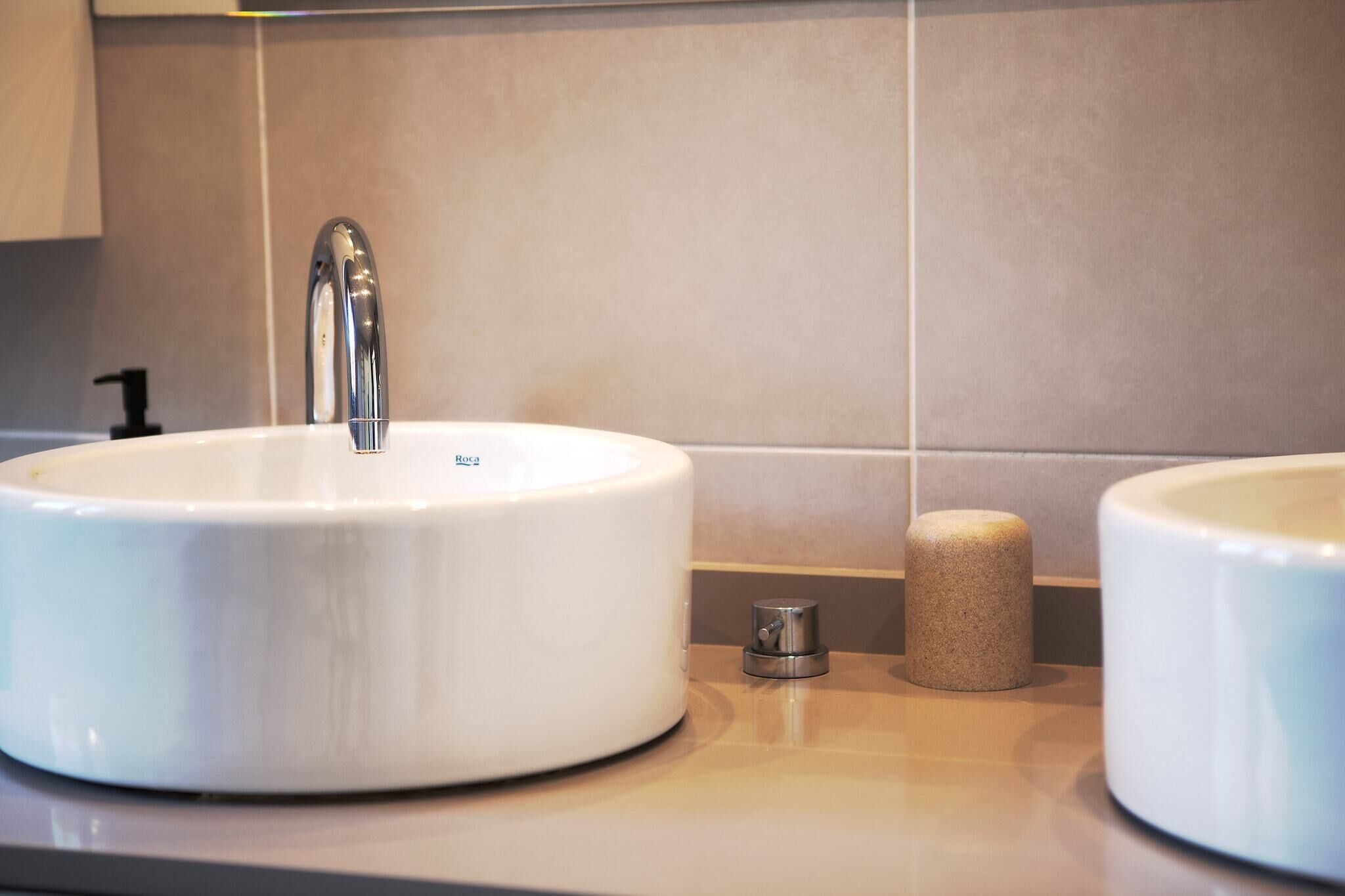 A bathroom with a white sink, a faucet, and a soap dispenser.