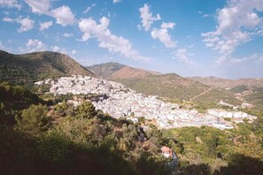 A town nestled in a valley with a dense cluster of buildings, surrounded by hills and greenery. - Sunny Terrace Apartment (Ojen)