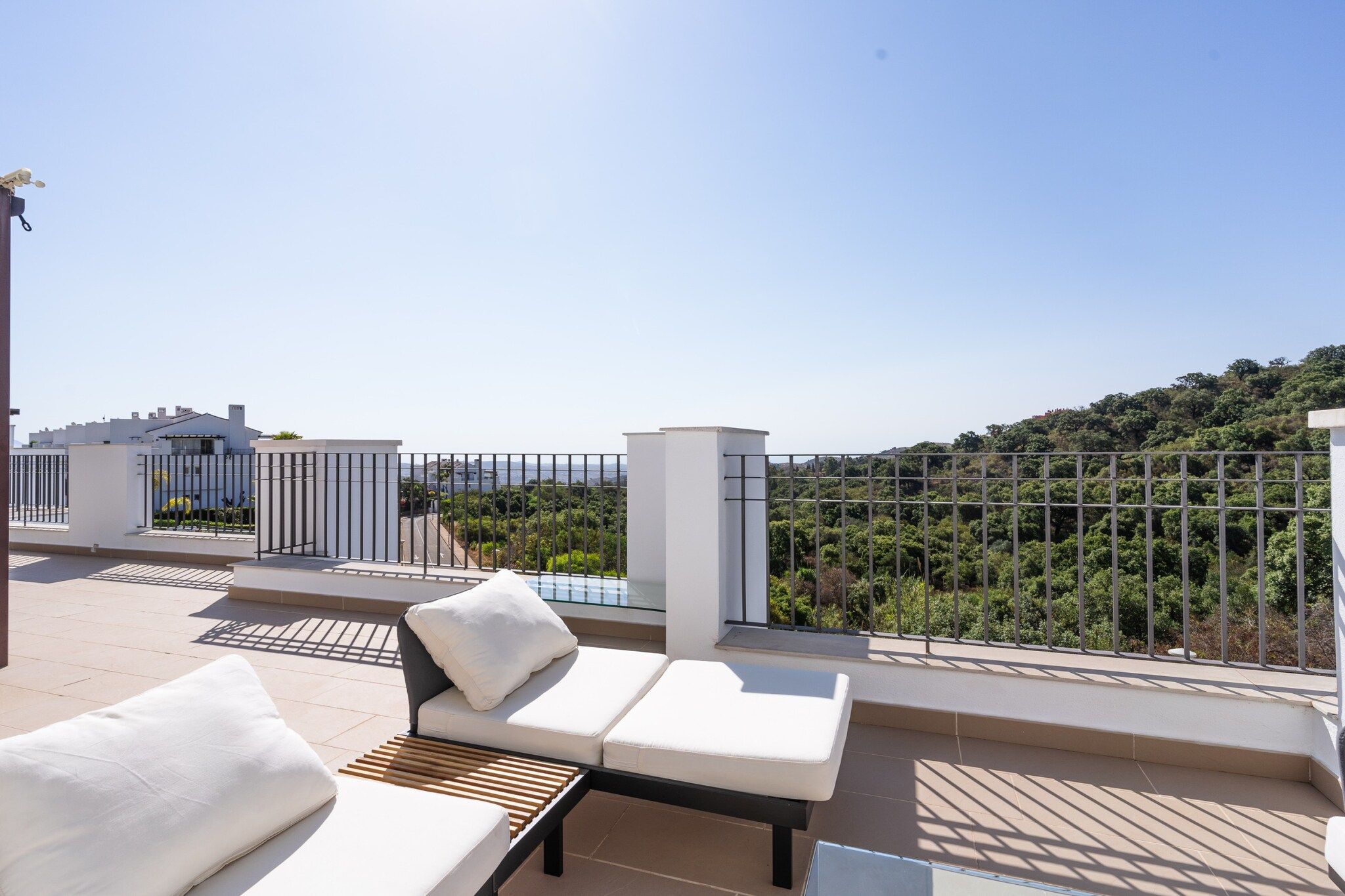 A rooftop terrace with outdoor seating and a view of a hillside.