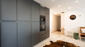 Una cocina moderna con gabinetes grises, electrodomésticos integrados y un tapete de cuero de vaca.