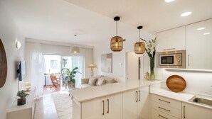 A modern kitchen with white cabinetry, a central island, pendant lighting, and a built-in microwave.