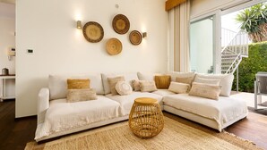 A modern living room with a white sectional sofa, a woven coffee table, and wall-mounted decorative plates.