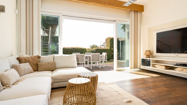 A modern living room with a sectional sofa, a TV, and a dining area with chairs and a table.
