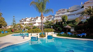 Ein Swimmingpool mit blauem Wasser, umgeben von Liegestühlen und Palmen.