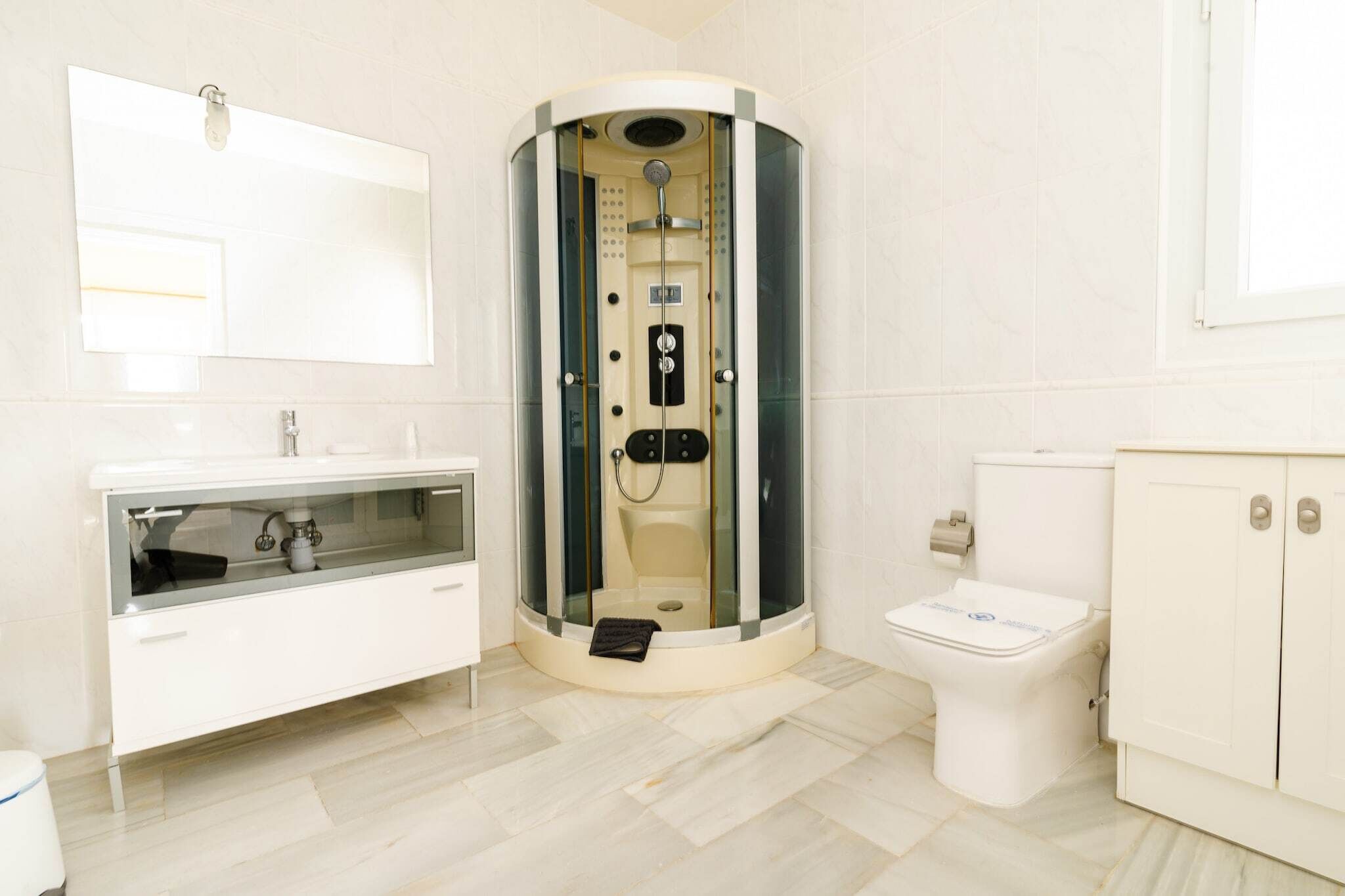 Een moderne badkamer met een douchekabinet van glas, een wit badkamermeubel met spiegel en een toilet.