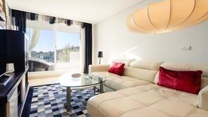 En moderne stue med sofa, glasbord og fjernsyn.