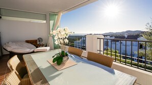 En balkon med et bord, stole, en seng og en potteplante.