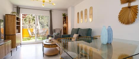 Un salon moderne avec une table à manger en verre, un canapé et une grande fenêtre.