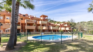 A residential building with multiple balconies, a swimming pool, and palm trees. - Marbella Coastal Comfort (Marbella)