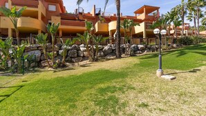 A hotel with multiple balconies, palm trees, and a well-maintained lawn. - Marbella Coastal Comfort (Marbella)